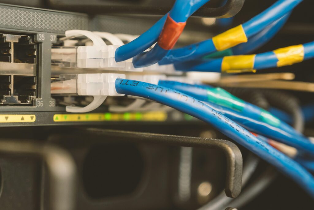 Network switch and blue ethernet cable with white tips connected to system for maintenance